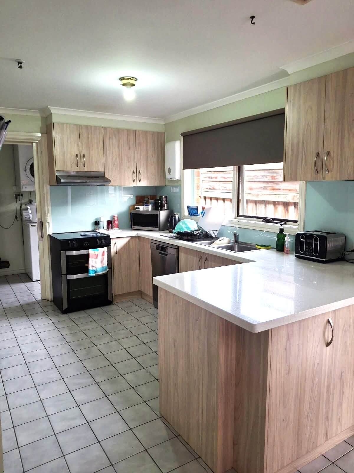A kitchen with wooden cupboards and a white tiled floor