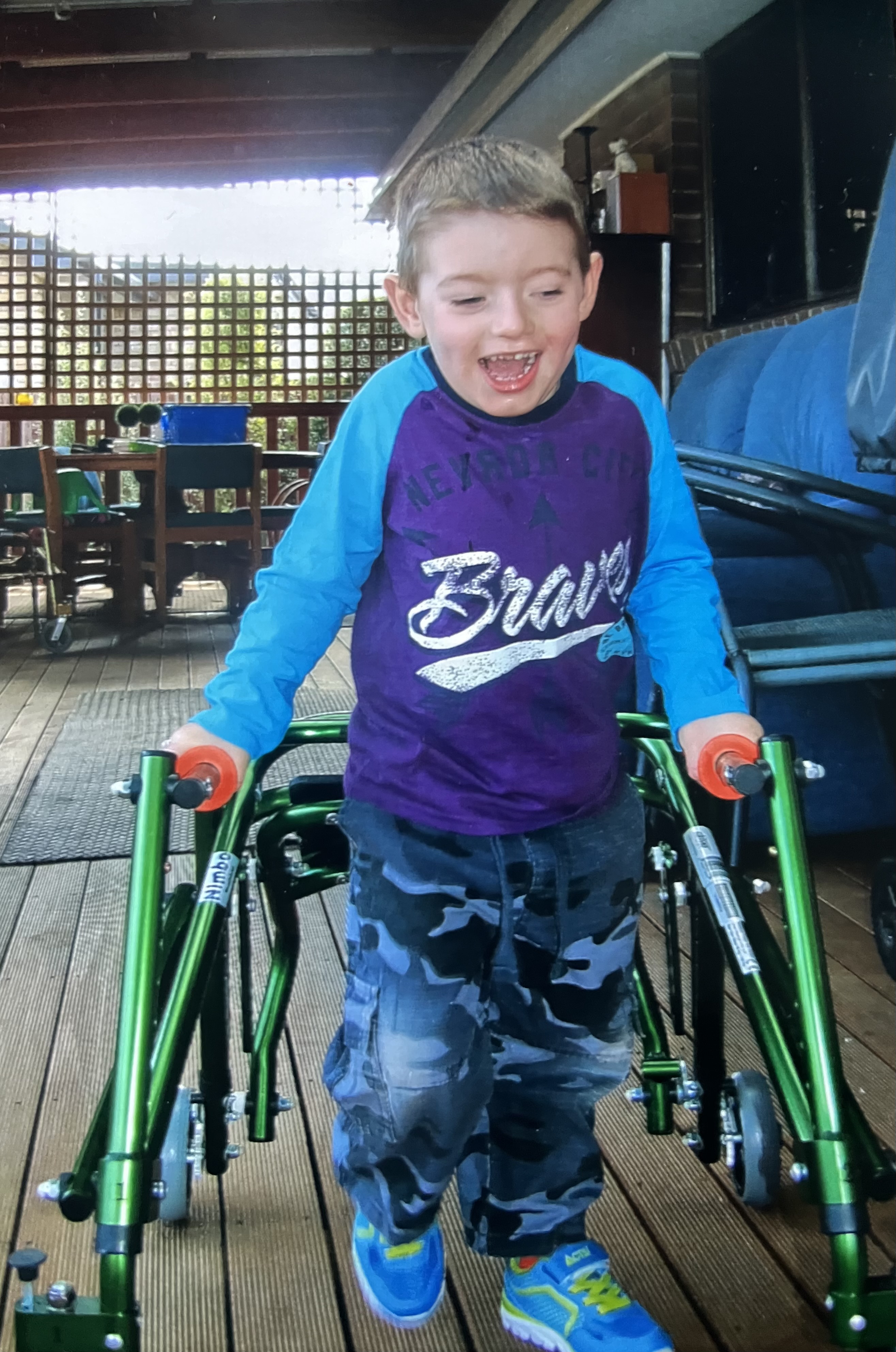A boy on a house deck using his walker to walk