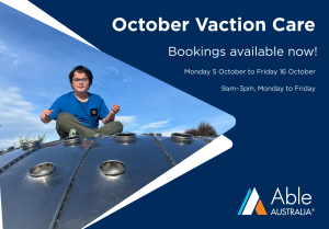 A person wearing a blue T-shirt and glasses sits on top of a large blue playground structure outdoors under a bright blue sky with scattered clouds. The image is positioned on the left side of a promotional banner. On the right side, white text on a dark blue background reads: "October Vacation Care", "Bookings available now!", "Monday 5 October to Friday 16 October", and "9am–3pm, Monday to Friday". The Able Australia logo appears in the bottom right corner. White graphic shapes frame the photograph and separate it from the text.